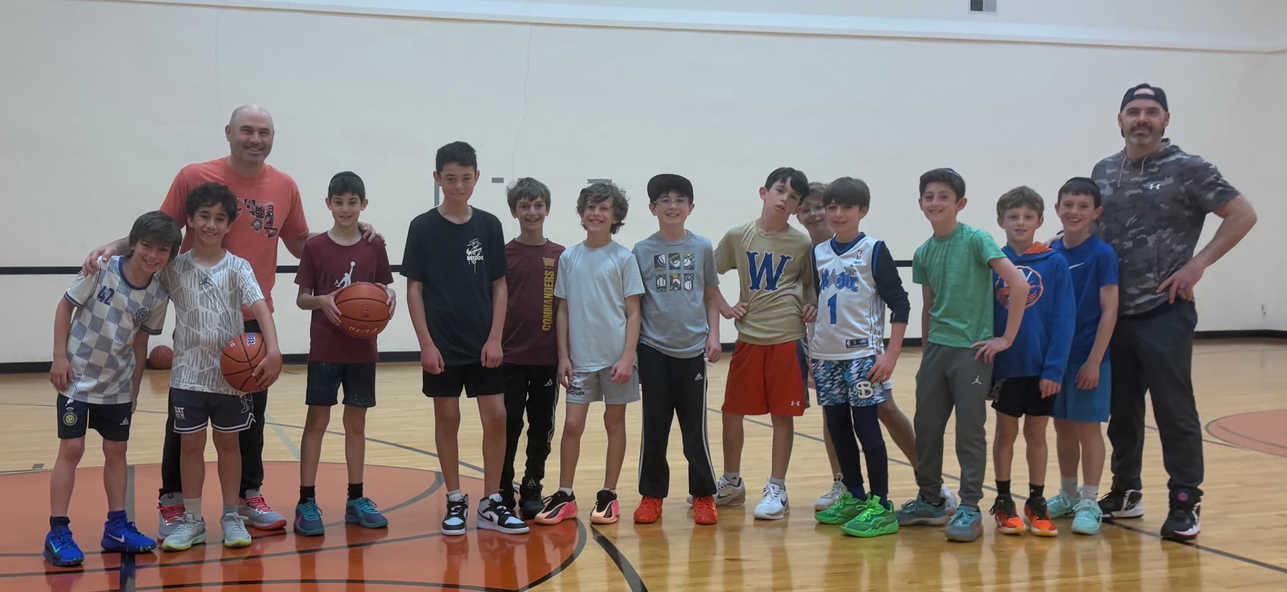 Coach Harry with a group of athletes on the court at a Harry's Hoops clinic